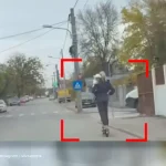 img - Femeie cu bebeluș în brațe, filmată pe trotineta electrică